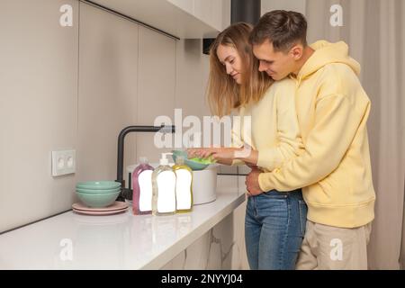 Man and woman washing the dishes using dishwashing liquid with blank label Stock Photo