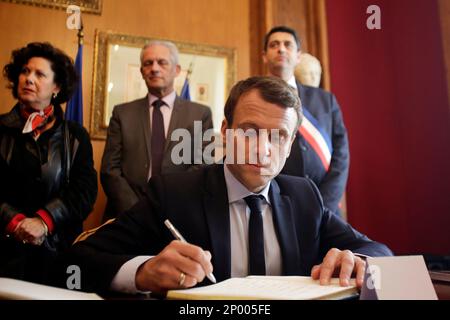 French independent centrist presidential candidate Emmanuel Macron signs the guest book after visiting the French martyr village of Oradour-sur-Glane, central France, Friday, April 28, 2017. France's troubled wartime past is taking center stage Friday in the country's highly charged presidential race, as centrist Emmanuel Macron visited the site of France's worst Nazi massacre and Marine Le Pen's far-right party suffered a new blow over alleged Holocaust denial. (Pascal Lachenaud/Pool Photo via AP)