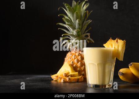 Pineapple lassie or smoothie on black background. Traditional healthy vegan asian beverage made of pineapple, yogurt and ice. Copy space. Stock Photo