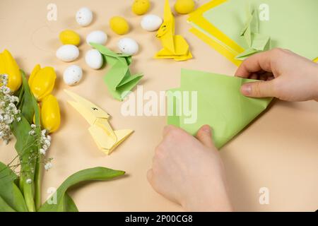 Handicrafts from paper for Easter - origami, making figurines of Easter bunnies, hands close-up Stock Photo