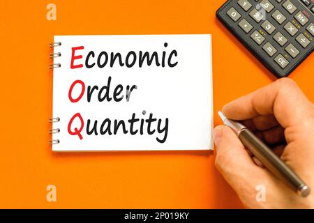 EOQ economic order quantity symbol. Concept words EOQ economic order quantity on white note on beautiful orange background. Businessman hand. Business Stock Photo