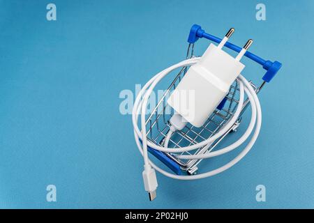 A phone charger in a supermarket cart on a blue background Stock Photo