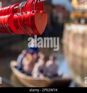 Red heart-shaped locks on a fence along the Lauch River in Colmar Stock Photo