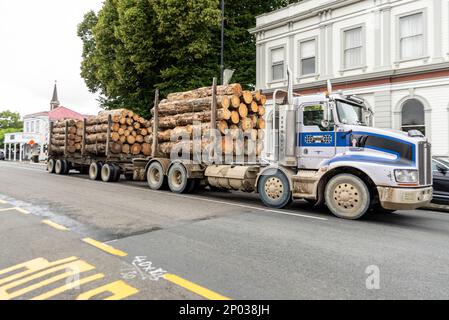 Logging truck traveling through Greytown on State Highway 2, New Zealand. Kenworth lorry and trailer hauling forestry logs through town Stock Photo