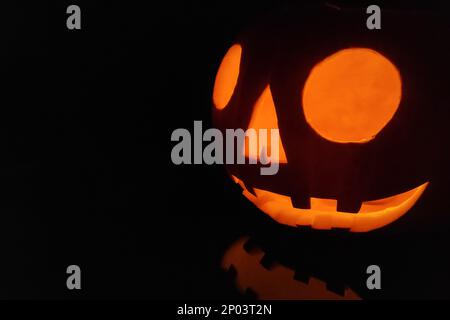 Close-up on a Jack O' Lantern reflecting on a black surface. Stock Photo