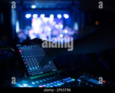 Sound Technician operating audio board at music festival stage Stock Photo