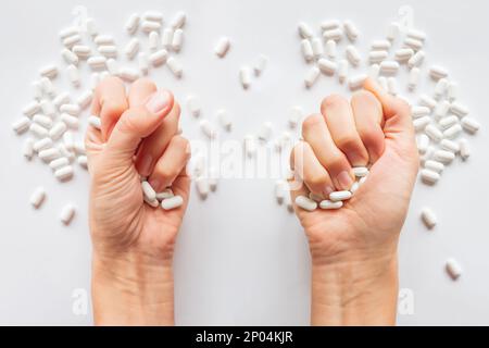 Palm hands full of white scattering pills. Woman gripes hand with capsules with medicines on light background. Flat lay, top view. Stock Photo