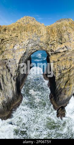 The Pacific Ocean washes through a rocky, natural arch off the scenic, northern coast of Oregon, not far from the town of Tillamook. Stock Photo