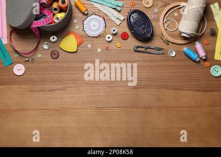 Flat lay composition with different sewing accessories on wooden background. Space for text Stock Photo