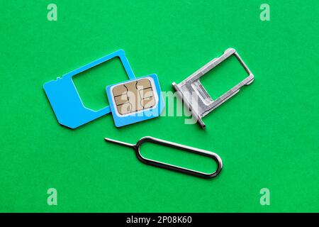 SIM card, tray and ejector on green background, flat lay Stock Photo