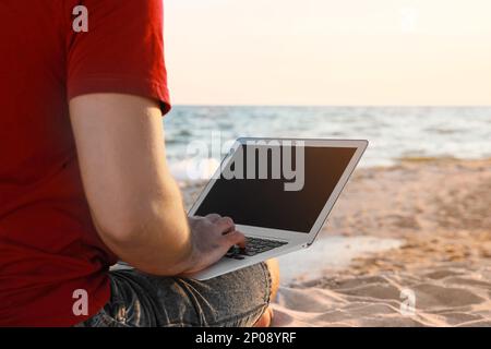 Man working with laptop on beach, closeup Stock Photo