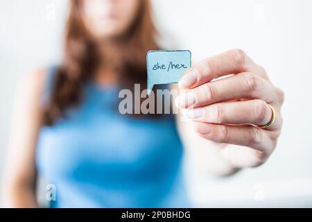 woman holding gender identity pronouns She Her on paper speech bubble, concept of respecting people's identity in society Stock Photo