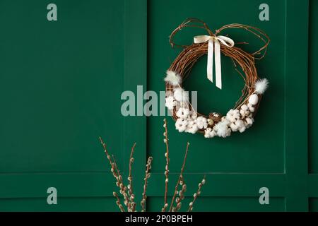 Willow branches and Easter wreath on green wall Stock Photo