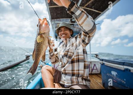 big grouper caught by an Asian angler with fishing rod Stock Photo