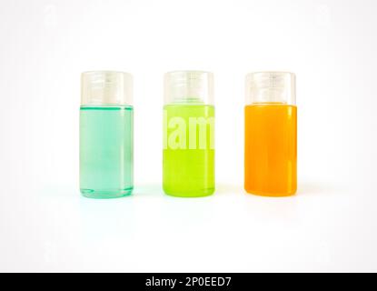 Three small plastic bottles full of colorful cosmetic products with copy space. Body care and beauty products for bath in blank containers - shower ge Stock Photo
