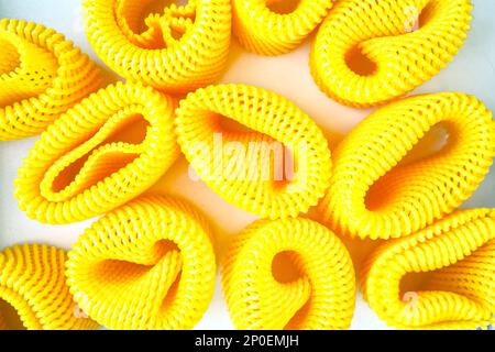 Many yellow EPE fruit nets abstract close-up background. Expanded polyethylene foam net pile Stock Photo