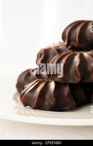 Pile of marshmallows glazed with chocolate. Many coated elegant zephyr dessert isolated on white. Sweet elegant dessert on a plate Stock Photo