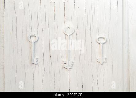 Three keys trendy decor on an old gray cracked door, vintage abstract design cluse-up background. Choice of path concern Stock Photo