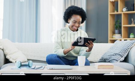Woman using a digital tablet at home. Beautiful and happy young female student smiling and laughing while browsing apps, scrolling social media and Stock Photo