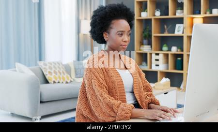 Young woman working remotely on a computer from home. Dedicated student browsing the internet while doing research and planning for an online course Stock Photo