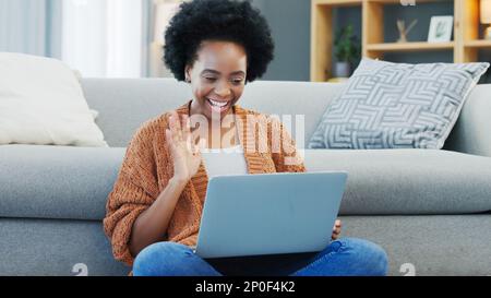 Happy African American woman using laptop and waving on a video call in a living room. Young black female having a casual chat with friends at home Stock Photo