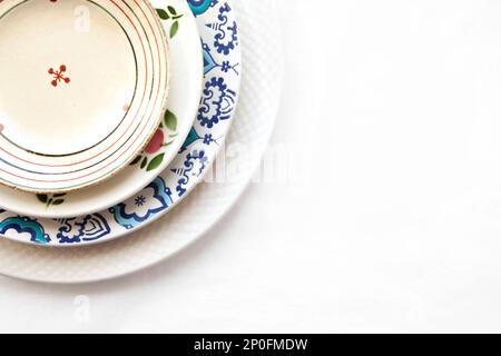 Stack of empty ceramic plates isolated on white background with copy space. Cheerful colorful dishes decorated with floral pattern. Beautiful vintage Stock Photo