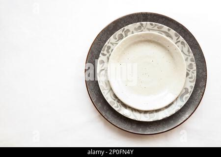 Stack of empty ceramic plates isolated on white background with copy space. Stylish gray dishes decorated with floral pattern. Beautiful vintage crock Stock Photo