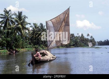 A boat man carrying sand on a dhow, traditional sailing vessel, Backwaters of Kollam, Quilon, Kerala, India Stock Photo