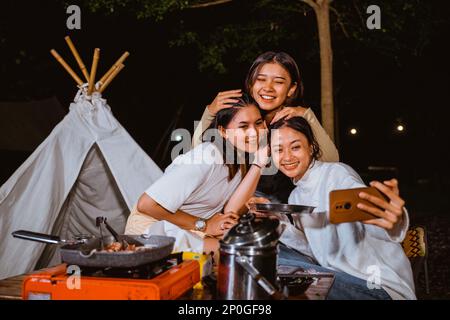 woman in cardigan smiling and embrace her friends heads Stock Photo