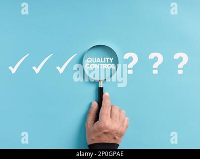 Business technology and industrial quality control in production. Hand holds magnifier focusing on the word quality control next to question mark and Stock Photo