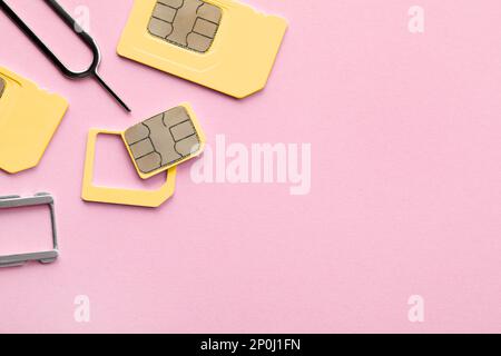 SIM card, tray and ejector on pink background, flat lay. Space for text Stock Photo