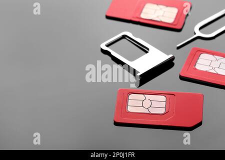 SIM cards, tray and ejector on grey background. Space for text Stock Photo