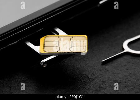 SIM card, mobile phone and ejector on black table, closeup Stock Photo