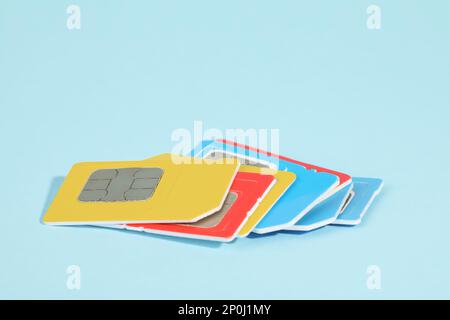 Different SIM cards on light blue background, closeup Stock Photo