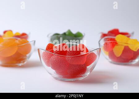 Different delicious gummy candies in bowls on white background, closeup Stock Photo