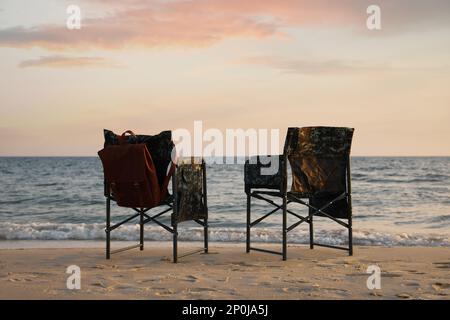 Camping chairs and backpack on sandy beach near sea Stock Photo