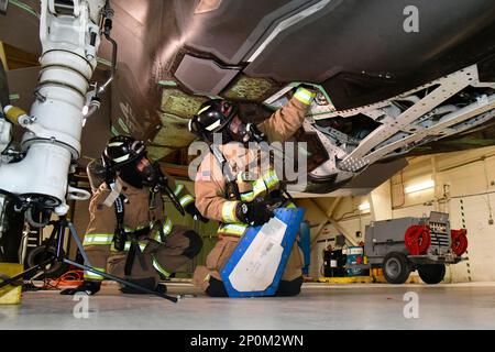 (Left to right) Senior Airman Dustin Fahlbusch, fire protection journeyman, and Duncan Hutchinson, firefighter, both with 775th Civil Engineering Squadron Fire Department, practice emergency engine shutdown on a salvaged aircraft Jan. 25, 2023, at Hill Air Force Base, Utah. This was one of several scenarios practiced during an emergency responder working group exercise attended by first responders from across the Air Force to explore emergency engine shutdown and aircrew extraction best practices specific to F-35 aircraft. Stock Photo