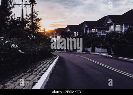 Modern cottages row road sidewalk two story buildings residential villas village New Estate Reflection dawn Sun in windows  Stock Photo