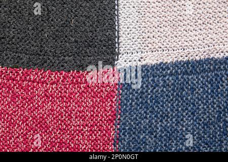 Traditional knitting background. Woolen knitted cloth of white, black, blue and red color Stock Photo