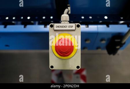 Button with the words EMERGENCY STOP next to a conveyor belt Stock Photo