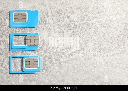 SIM cards on light grey stone background, flat lay. Space for text Stock Photo