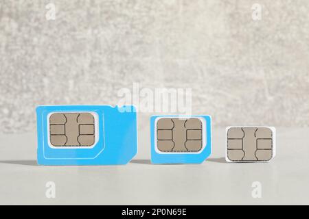 Different color SIM cards on light grey table. Space for text Stock Photo