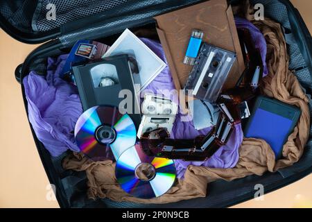 Multiple modern and retro storage devices in baggage suitcase. Family memories on different cassette, pendrive, hdd, memory cards, external USB disks. Top view. Stock Photo