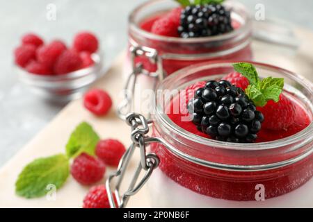 Delicious panna cotta with fruit coulis and fresh berries in glass jars, closeup Stock Photo