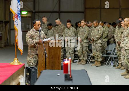 U.S. Army Staff Sgt. Anthony Montalvo, a religious affairs specialist with the 369th Sustainment Brigade, Task Force Hellfighter, delivers the invocation at a lectern during a Non-Commissioned Officer (NCO) Induction ceremony held at Camp Buehring, Kuwait, Feb. 18, 2023. The NCO induction ceremony is a celebration of the newly promoted joining the ranks of a professional noncommissioned officer corps and emphasizes and builds on the pride all share as members of such an elite corps. The ceremony also serves to honor those men and women of the NCO Corps who have served with pride and distinctio Stock Photo