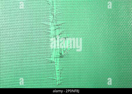 Torn window screen against green background, closeup Stock Photo