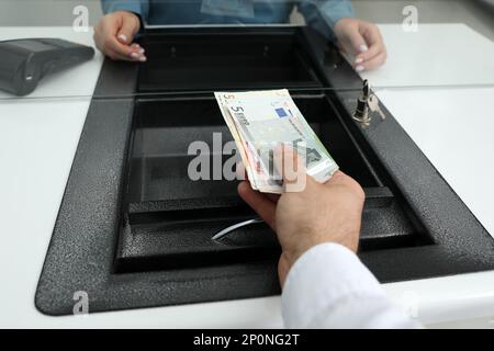 Cashier giving money to woman at currency exchange window in bank, closeup Stock Photo