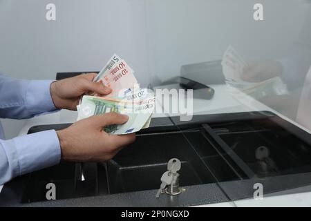 Cashier with money at currency department window in bank, closeup Stock Photo