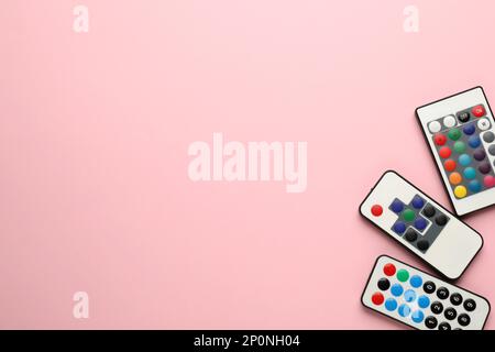 Different remote controls on pink background, flat lay. Space for text Stock Photo