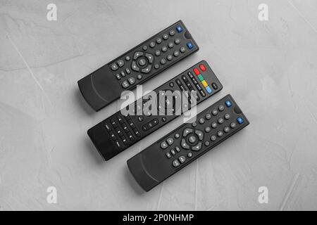 Modern tv remote controls on grey table, flat lay Stock Photo